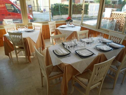a dining room with two tables and chairs and windows at Hotel Ristorante La Terrazza in Lido di Camaiore