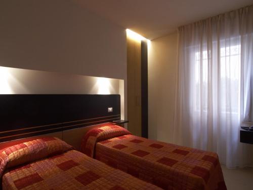 a hotel room with two beds and a window at Hotel Villa Lalla in Rimini