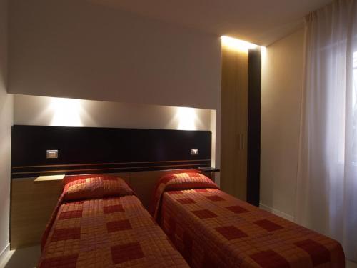 a hotel room with two beds and a headboard at Hotel Villa Lalla in Rimini