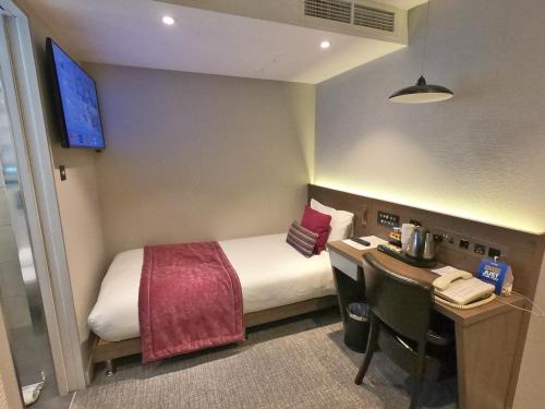 a hotel room with a bed and a desk with a telephone at Best Western Plus Delmere Hotel in London