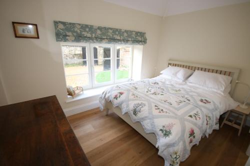 a bedroom with a bed and a window at Bolton's Cottage in Oakham
