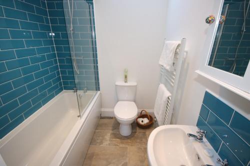 a bathroom with a toilet and a tub and a sink at Bolton's Cottage in Oakham