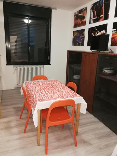 a dining room table with orange chairs and a table with at Enjoy Padova in Padova