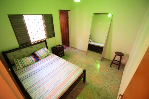 Dormitorio pequeño con cama y espejo en Casa do Neguito, en Olímpia