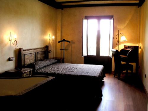 1 dormitorio con cama, ventana y escritorio en Hotel Rural y SPA Kinedomus Bienestar en Aranda de Duero