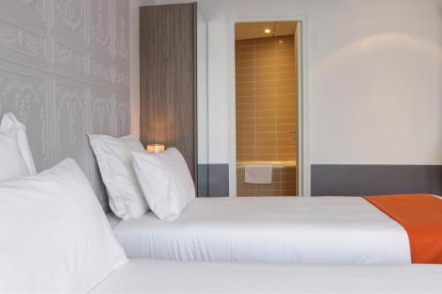 a bedroom with two beds with white pillows at Contact Hôtel Alizé Montmartre in Paris