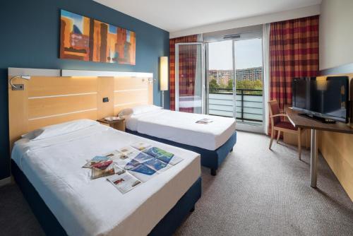 a hotel room with two beds and a flat screen tv at Idea Hotel Torino Mirafiori in Turin