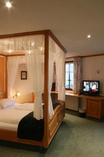 フェルトベルクにあるHotel Adler Bärentalのベッドルーム(天蓋付きベッド1台、テレビ付)