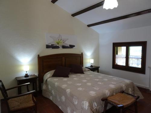 a bedroom with a bed and two chairs and a window at Mas El Bosquet in Joanetes