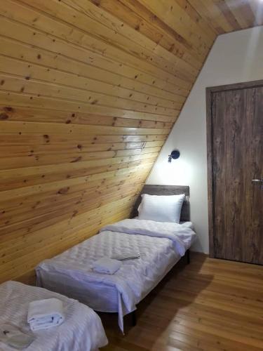 two beds in a room with a wooden wall at Hotel TWINS Achkhoti in Stepantsminda