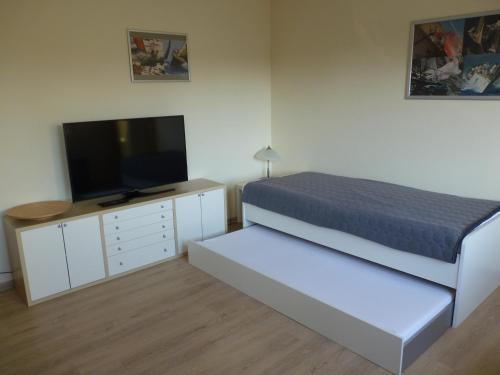 a bedroom with a bed and a flat screen tv at Cafe und Pension Blohm in Greifswald