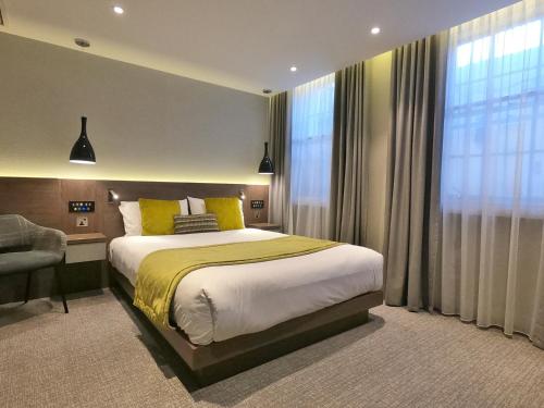 um quarto com uma cama, uma cadeira e uma janela em Best Western Plus Delmere Hotel em Londres