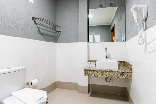 a bathroom with a sink and a toilet and a mirror at Hotel Trevita Foz in Foz do Iguaçu
