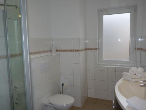 a bathroom with a toilet and a sink and a window at Cafe und Pension Blohm in Greifswald