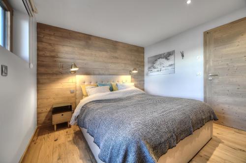 a bedroom with a large bed with a wooden wall at Chalet Caprice in Combloux
