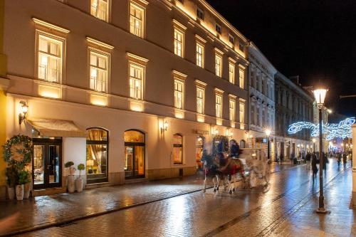 a city street at night with people walking down the street at Balthazar Design Hotel in Kraków
