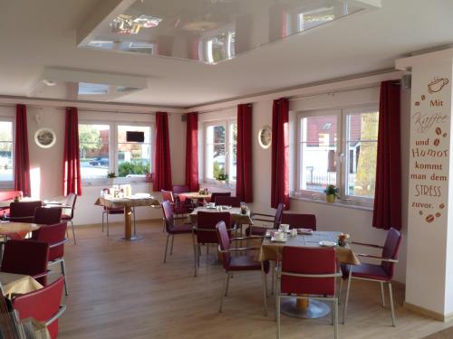 un restaurante con cortinas rojas, mesas y sillas en Cafe und Pension Blohm, en Greifswald