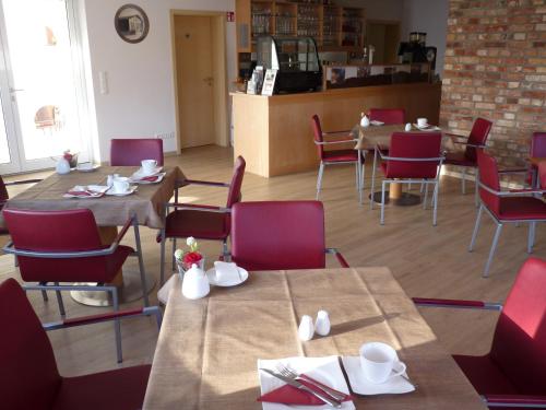 a dining room with tables and red chairs at Cafe und Pension Blohm in Greifswald