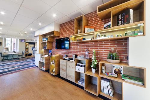 an office lobby with a brick wall and shelves at ibis Styles Toulouse Lavaur in Lavaur