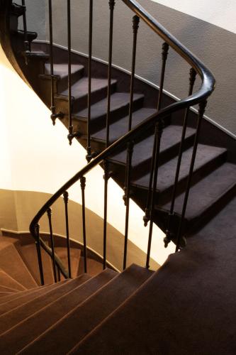 a stairway with a black metal railing and shadows at Contact Hôtel Alizé Montmartre in Paris