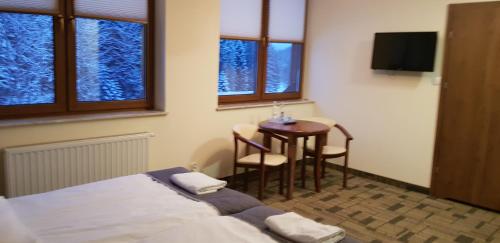 a hotel room with a bed and a table and windows at Centrum Promocji Leśnictwa w Mucznem in Lutowiska
