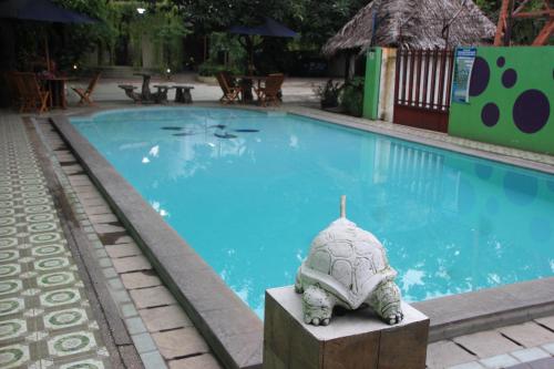 une statue de tortues près d'une piscine dans l'établissement Hotel Pesona Merak, à Merak