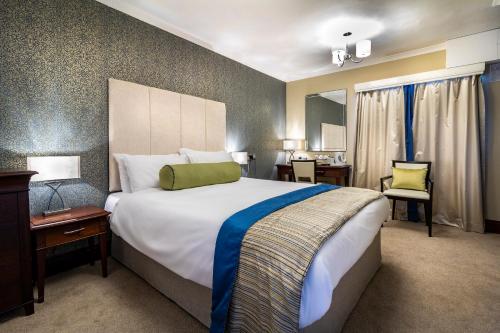 a hotel room with a large bed and a desk at Best Western The Shrubbery in Ilminster