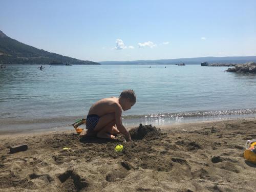 a boy playing in the sand on the beach at Cozy apartments with seafront terraces in Omiš