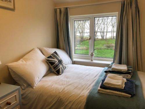 a bedroom with a bed with pillows and a window at Marsh View Cottage, Aldeburgh in Aldeburgh