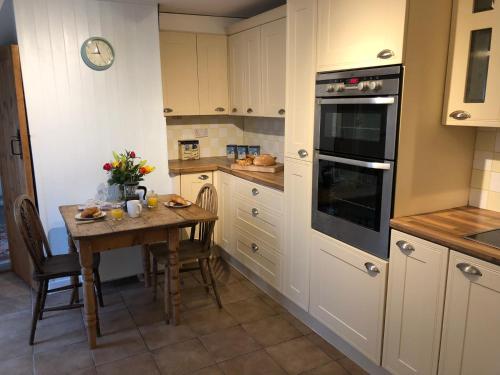 a kitchen with a table with flowers on it at Marsh View Cottage, Aldeburgh in Aldeburgh