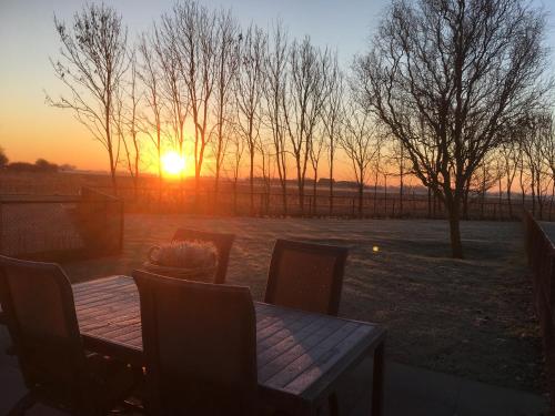 a table and chairs with the sunset in the background at Mooi, vrij gelegen vakantiehuis dichtbij zee en strand! in Aagtekerke