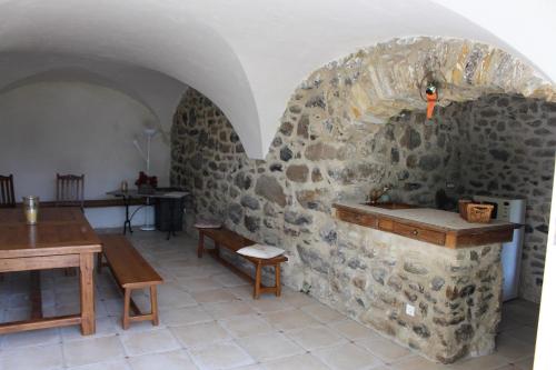 a room with a stone wall with a table and benches at L'Attrape Reve in Saint-Vincent-de-Barrès
