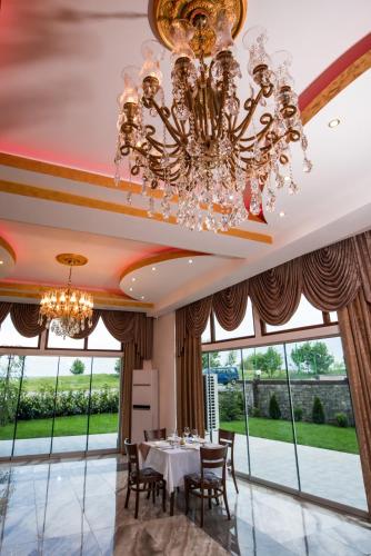 a dining room with a chandelier and large windows at SPA Kompleks Raiski Kat in Dimitrovgrad