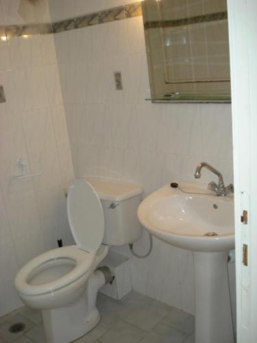a white bathroom with a toilet and a sink at Niki Apartments in Polychrono