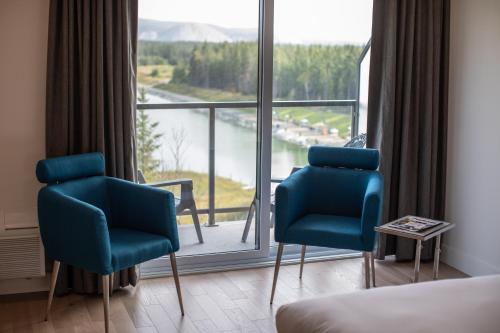 a room with two blue chairs and a large window at Hôtel du Domaine, centre de villégiature et de congrès in Thetford Mines
