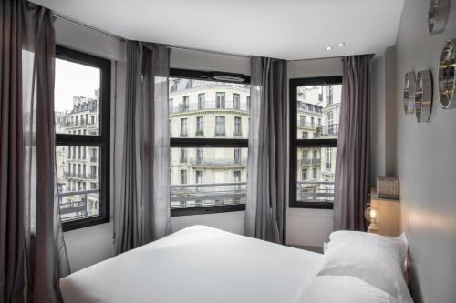 une chambre avec un lit et deux grandes fenêtres dans l'établissement Habitat Parisien - Appartement Opéra Galeries Lafayette, à Paris