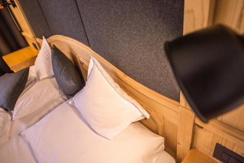 a bed with white sheets and black pillows at Vitaurina Royal Hotel in Molini di Tures