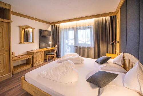 a hotel room with two beds and a desk at Vitaurina Royal Hotel in Molini di Tures