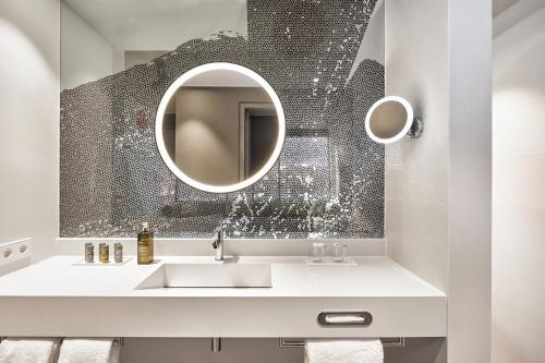 a bathroom with a sink and a mirror at H4 Hotel Mönchengladbach im BORUSSIA-PARK in Mönchengladbach