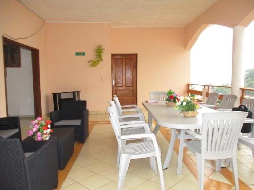 a dining room with white chairs and a table at Centre d'Accueil Deo Gratias in Yaoundé