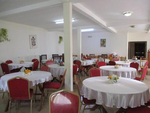 a dining room with white tables and red chairs at Centre d'Accueil Deo Gratias in Yaoundé