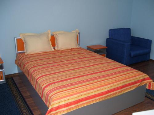 a bedroom with a bed and a blue chair at Kestenite Family Hotel in Samokov
