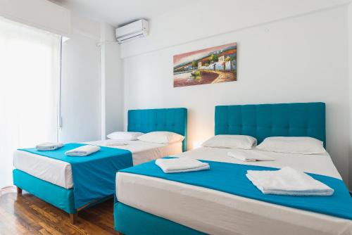 two beds in a room with blue accents at Super Paradise Apartments in Athens