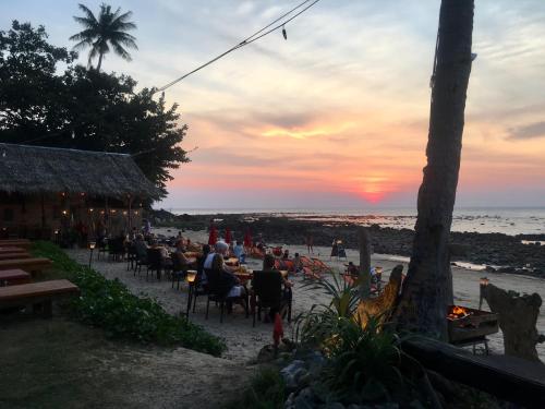 a group of people sitting at a restaurant on the beach at Nautilus Right on the Beach - Adult Only - SHA Extra Plus in Ko Lanta