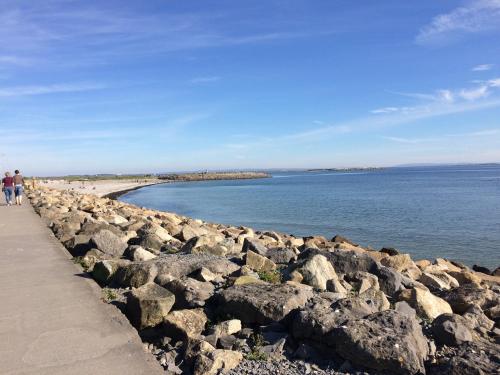 a group of people walking along a rocky beach at Galway City Self Catering - Salthill in Galway