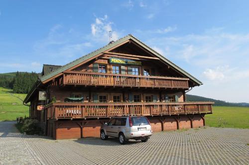 a car parked in front of a large wooden building at Penzion Haltmar in Ostružná