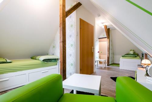 ein kleines Zimmer mit einem Bett und einem grünen Stuhl in der Unterkunft Ferienwohnung Alexandra in Heilbad Heiligenstadt