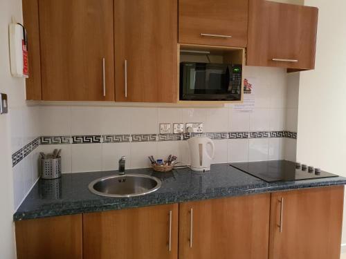 a kitchen counter with a sink and a microwave at Grand Plaza Serviced Apartments in London
