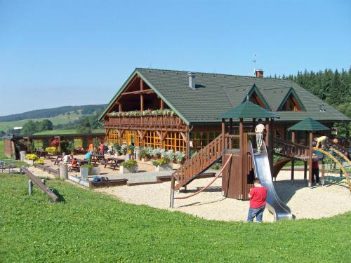 a playground with a slide in front of a building at Penzion Haltmar in Ostružná