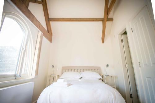 a bedroom with a white bed with a window at The Hayloft in Skipton